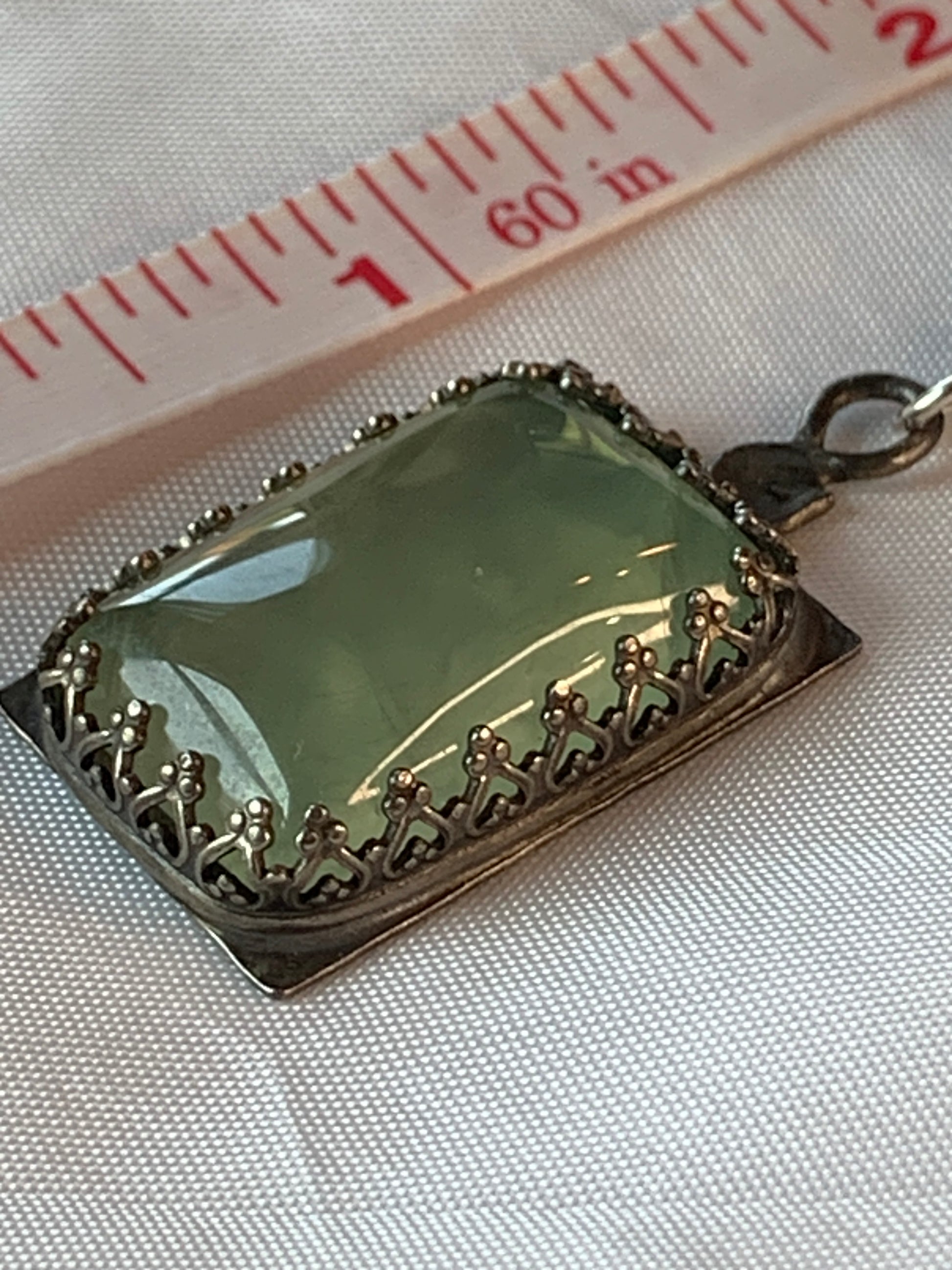 This one-of-a-kind Prehnite pendant is sure to make a statement. Handcrafted from 925 Sterling Silver and a large Prehnite gemstone, this pendant will bring an air of sophistication to any outfit. Enjoy the unique beauty of this piece - no two are exactly alike!