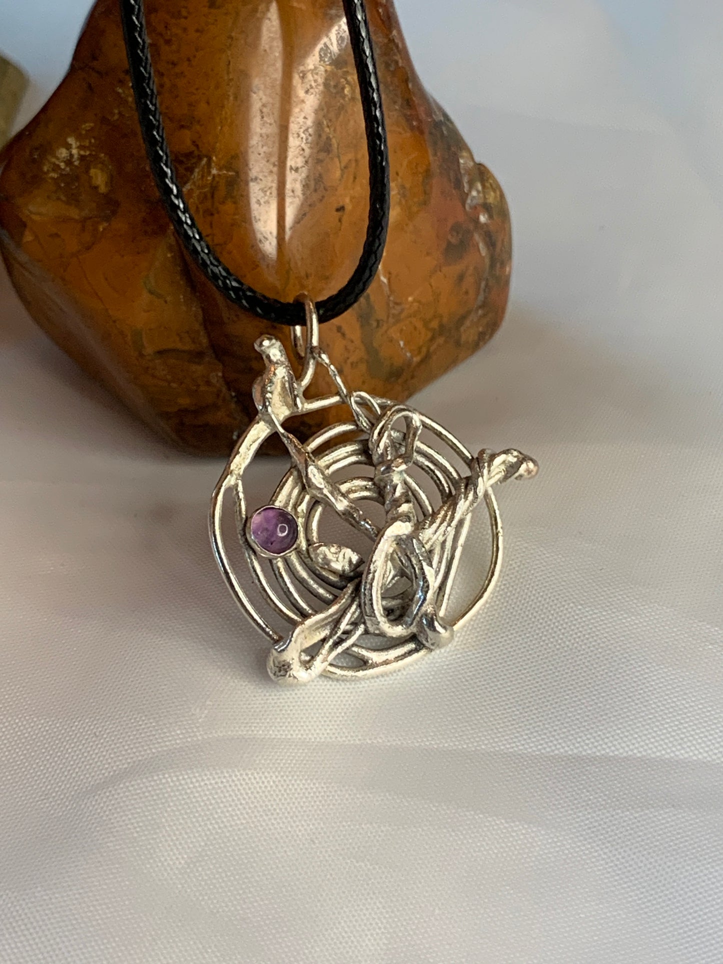 The pendant features an abstract fused spiral design, meticulously handcrafted from sterling silver, symbolizing creativity and individuality. At its center lies a luminous Amethyst gemstone, renowned for its calming and spiritual properties, enhancing intuition and inner peace.